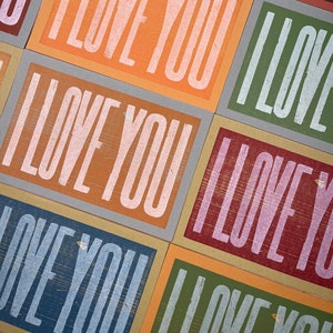 A grid of multi-colored rainbow oversized hand printed letterpress card prints that all read I Love You in white ink.