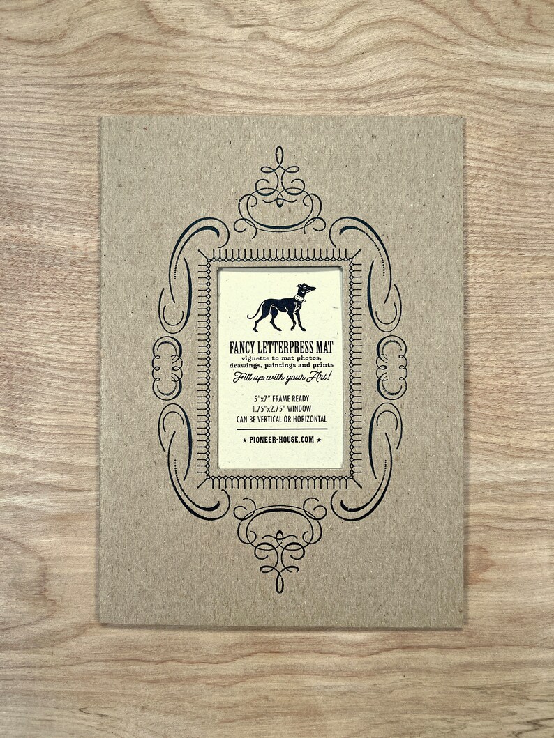Peut inclure: Un tapis en papier brun avec un cadre d&eacute;coratif noir et une illustration en noir et blanc d'un chien. Le texte "Fancy Letterpress Mat" est imprim&eacute; sur le tapis, ainsi que des instructions pour l'utiliser et le site Web "pioneer-house.com".