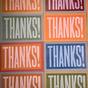 Puede incluir: Seis tarjetas con la palabra "THANKS!" impresa en blanco sobre fondos de diferentes colores. Los fondos son naranja, rojo, verde, azul, naranja y verde.