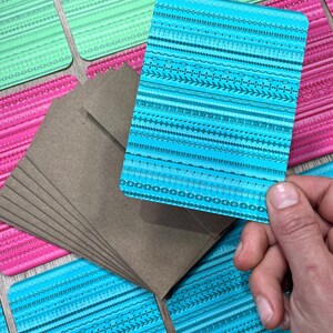 May include: A stack of brown envelopes with a blue and white patterned card on top. The card has a geometric design with lines and shapes.