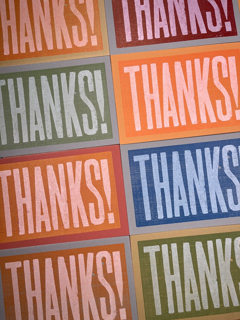 Puede incluir: Seis tarjetas con la palabra "THANKS!" impresa en letras blancas. Cada tarjeta tiene un fondo de color diferente: rosa, verde, naranja, azul, marr&oacute;n y verde claro.