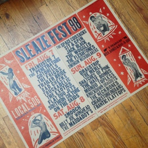 May include: A vintage-style poster for Sleaze Fest 98, featuring a red and beige color scheme. The poster lists bands and event details for the music festival, with illustrations of figures in rockets. The text includes the dates, times, and location.