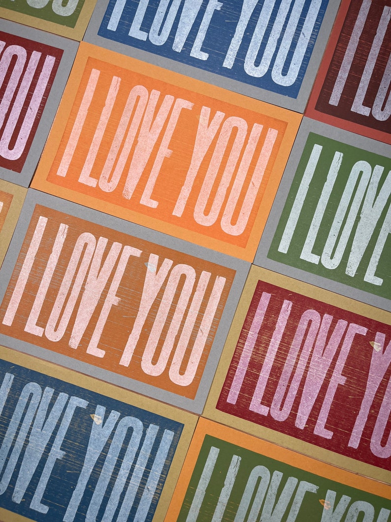 A grid of multi-colored rainbow oversized hand printed letterpress card prints that all read I Love You in white ink.