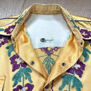 Camisa vaquera NATHAN TURK de la década de 1930, rara, con bordado de punto de cadena floral morado y satén dorado vintage, broches de esmalte, ropa de escenario de alta costura vaquera y vaquera.