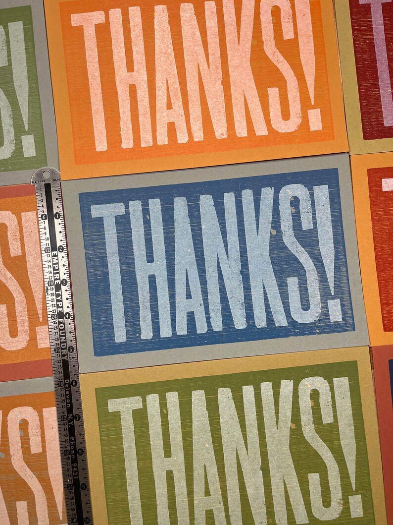 Puede incluir: Tres tarjetas con la palabra "THANKS!" impresa en blanco sobre fondos de colores diferentes. Las tarjetas son naranja, azul y verde.