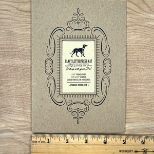 Peut inclure: Un tapis en carton brun avec un cadre orn&eacute; noir et une silhouette noire de chien &agrave; l'int&eacute;rieur. Le texte indique "Fancy Letterpress Mat" et "Fill up with your Art!" Le tapis mesure 5 pouces par 7 pouces et a une fen&ecirc;tre de 1,75 pouce par 2,75 pouce. Le tapis peut &ecirc;tre utilis&eacute; verticalement ou horizontalement. L'adresse du site Web est "pioneer-house.com".