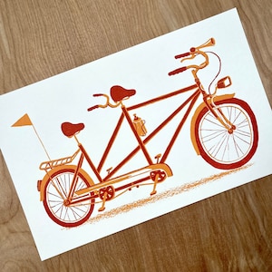 May include: A vintage-style orange and brown tandem bicycle with a single seat in the front and a second seat in the back. The bicycle has a water bottle holder and a bell.