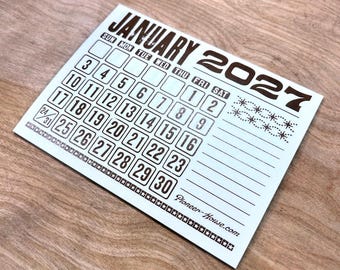 Może przedstawiać: Biały papierowy kalendarz na styczeń 2027 roku z ciemnobrązowym tekstem i grafiką. Siatka zawiera daty od 1 do 31, z napisem Pioneer-House.com w prawym dolnym rogu oraz ozdobną obwódką z gwiazdek wzdłuż dolnej krawędzi.
