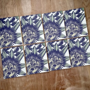 May include: Set of eight botanical illustrations featuring a stylized passionflower with blue and green hues. The illustrations are printed on white paper and have a vintage aesthetic.