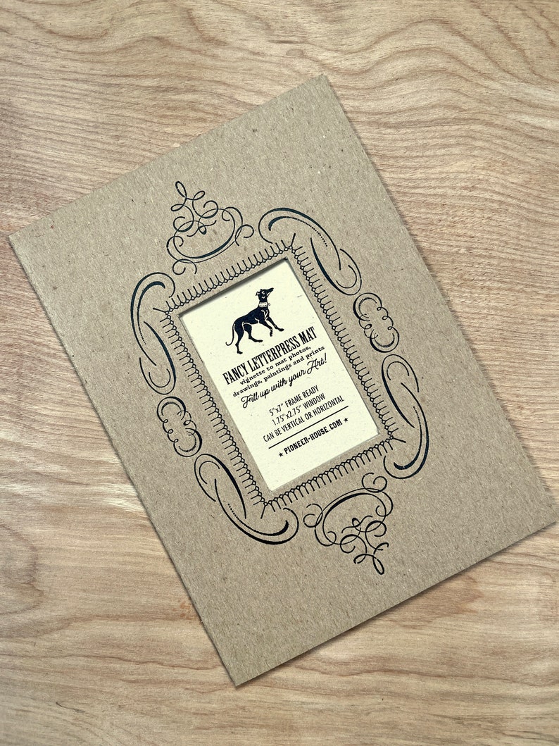 Peut inclure: Un tapis en papier brun avec un cadre d&eacute;coratif noir et une illustration en noir et blanc d'un chien. Le tapis est con&ccedil;u pour des photos, des dessins, des peintures et des impressions de 12,7x17,8 cm. Le texte "FANCY LETTERPRESS MAT" est imprim&eacute; sur le tapis. Le texte "Fill up with your art!" est imprim&eacute; sur le tapis. Le texte "5"x7" FRAME READY" est imprim&eacute; sur le tapis. Le texte "1.75"x2.75" WINDOW" est imprim&eacute; sur le tapis. Le texte "CAN BE VERTICAL OR HORIZONTAL" est imprim&eacute; sur le tapis. Le texte "PIONEER-HOUSE.COM" est imprim&eacute; sur le tapis.