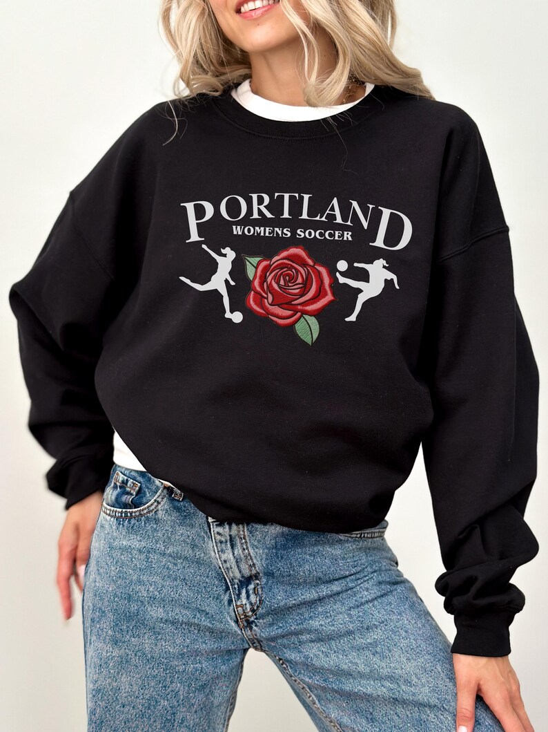 May include: Black sweatshirt with a white graphic print that says "PORTLAND WOMENS SOCCER" with a red rose and two football players.