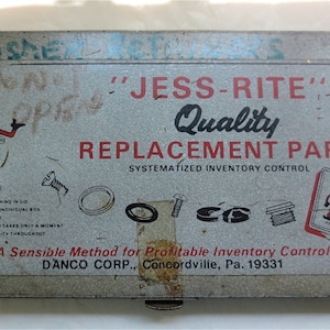 May include: A gray metal box with a red and white cartoon character on the front. The box is labeled "Jess-Rite Quality Replacement Parts" and "A Sensible Method for Profitable Inventory Control." The box is labeled "Danco Corp., Concordville, Pa. 19331."