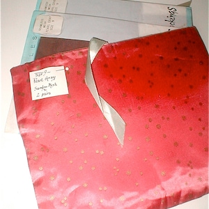 May include: A pink satin bag with gold stars printed on it. The bag has a white ribbon tied around it. A handwritten tag attached to the bag reads "Size 9 - Pearl Gray Seamless Mesh 2 pairs".