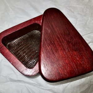 May include: A wooden box with a hinged lid. The box is made of dark red wood and has a mesh insert inside. The lid is shaped like a triangle.