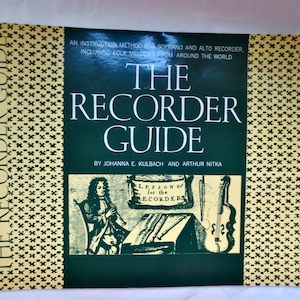 May include: A spiral-bound book titled "The Recorder Guide" with a black and gold cover. The cover features text and illustrations, including a person playing a recorder. The book is an instruction method for soprano and alto recorder.