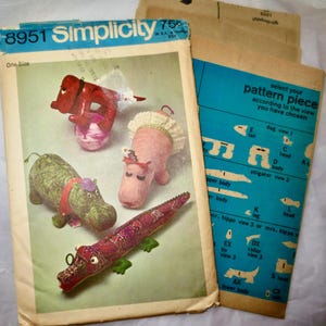 May include: Vintage Simplicity sewing pattern featuring stuffed animal designs, including a hippo, alligator, and dog. The pattern envelope is blue and white, with the number 8951. Includes pattern pieces and instructions.