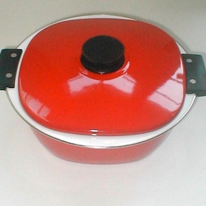 May include: A red oval-shaped casserole dish with a matching lid. The lid has a black knob and black handles on each side. The dish has a white rim and a silver trim.