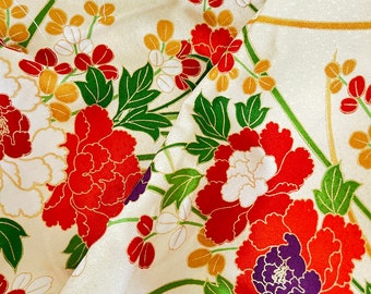 May include: Cream-colored fabric with a floral pattern featuring large red, white, and orange peonies with purple centers. Green leaves and gold accents complete the design. The fabric is folded, showing the pattern's repeat.