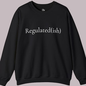 May include: A black long-sleeve crewneck sweatshirt featuring the white text Regulated(ish) printed across the center of the chest. The garment has a ribbed neckline, cuffs, and hem, with a small brand logo printed inside the collar area.