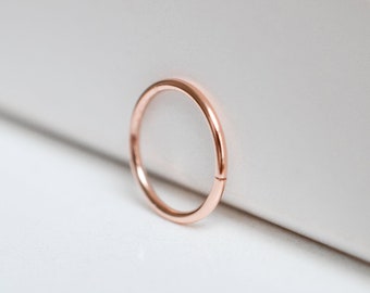 May include: A rose gold seamless ring, a type of jewellery often used for body piercings.