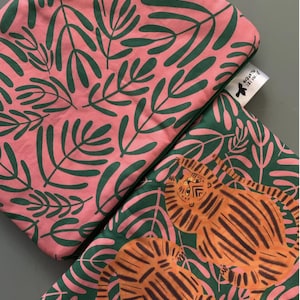 Op de afbeelding: Twee stoffen tasjes met een groen bladerenpatroon. Een tasje is roze met donkergroene bladeren en de andere is groen met roze bladeren en twee oranje tijgers.