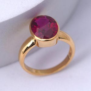 May include: A gold ring with a large oval-shaped ruby gemstone.