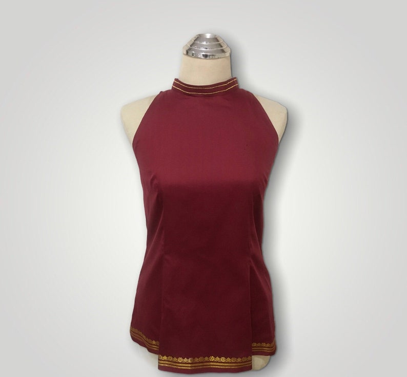 May include: A maroon sleeveless top with a high neckline and gold trim around the neck and hem.