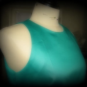 May include: A sleeveless, teal blue dress with a scoop neck.