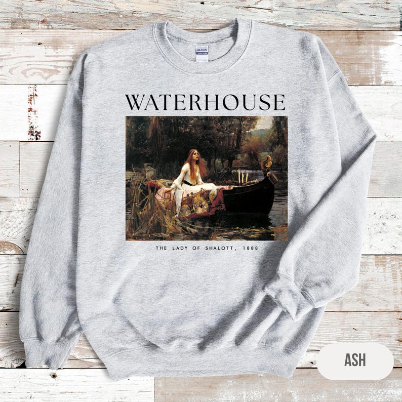 May include: A gray sweatshirt with a print of a painting by John William Waterhouse. The painting depicts a woman in a boat, titled "The Lady of Shalott, 1888". The text "WATERHOUSE" is printed above the painting.