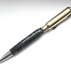 May include: A unique pen with a brass bullet casing barrel and a black and green marbled resin body. The pen features a silver tip and a brass clip, offering a distinctive writing instrument.