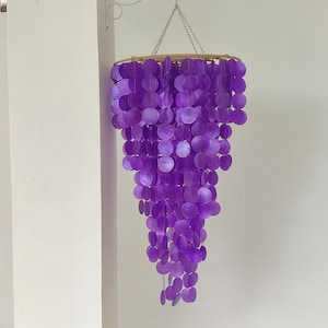 May include: A purple shell chandelier with multiple tiers of round shells hanging from a rope and metal chain.