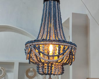May include: A tiered chandelier featuring vertical strands of alternating light blue and white wooden beads. The fixture has a dark metal frame and a central light bulb that emits a warm glow, illuminating the beads from within.