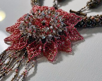 Könnte beinhalten: Eine Perlenkette mit einem großen rosa Blumenanhänger. Die Blume besteht aus kleinen Perlen und hat eine glitzernde Mitte.