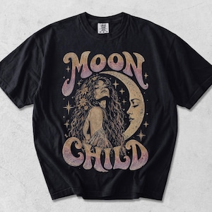 Könnte beinhalten: Ein schwarzes Kurzarm-T-Shirt mit einem Grafikdruck einer Person mit langem Haar und einer Mondsichel. Der Text MOON CHILD ist in einem Farbverlauf aus Violett, Orange und Gelb gedruckt. Kleine Sterne und Blumen umgeben die zentrale Figur.