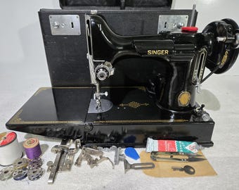 Puede incluir: Una máquina de coser Singer negra con detalles dorados y su maletín de transporte negro a juego. Incluye varios accesorios metálicos, varias bobinas de metal, dos carretes de hilo, una llave pequeña y un tubo de lubricante.