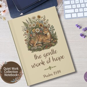 May include: A beige notebook featuring a central illustration of a brown deer resting amidst a colorful arrangement of wildflowers and greenery. Below the deer, the text reads the gentle work of hope and Psalm 119:114 in a dark brown script font.