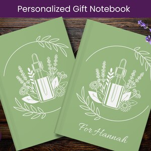 May include: Two sage green notebooks with white botanical illustrations and the text "Personalized Gift Notebook." One notebook is personalized with the name "For Hannah." The design includes a dropper bottle, flowers, and leaves.