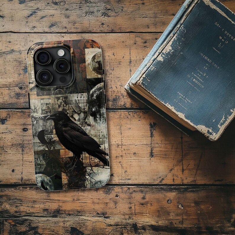 May include: A black phone case with a collage design featuring a raven, moons, and vintage-looking paper scraps. The case has a camera lens cutout.