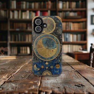 May include: A phone case with a vintage celestial map design. The case features a blue background with gold accents and a compass-like design. The case has a cutout for the phone's camera.