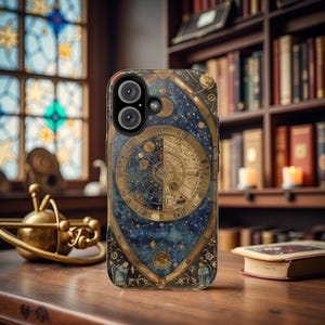 May include: A phone case with a celestial design featuring a gold and blue color scheme. The case has a circular design with a compass-like pattern and stars. The text "NOV. MON. DIE" is visible on the case.