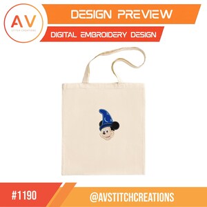 Op de afbeelding: Een cr&egrave;mekleurige draagtas met een gestikt ontwerp van een cartoonmuis met een blauwe tovenaars hoed. De tas heeft een eenvoudige handgreep en de tekst "DESIGN PREVIEW" en "DIGITAL EMBROIDERY DESIGN" zijn zichtbaar. Het logo van AV Stitch Creations staat linksboven.