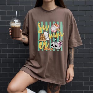 Cute Summerween ghost shirt design with striped background, ghost building sandcastle, ghost on float, skull coconut drink and tropical spooky summer aesthetic