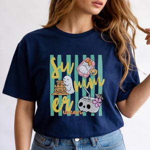 Cute Summerween ghost shirt design with striped background, ghost building sandcastle, ghost on float, skull coconut drink and tropical spooky summer aesthetic