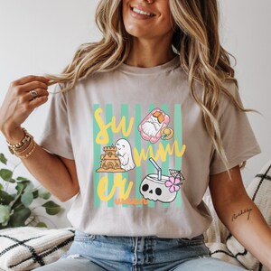 Cute Summerween ghost shirt design with striped background, ghost building sandcastle, ghost on float, skull coconut drink and tropical spooky summer aesthetic
