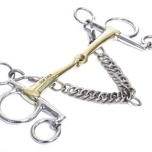 May include: A gold-coloured horse bit with a silver chain and two silver rings on each side. The bit is labelled "Top Tack".