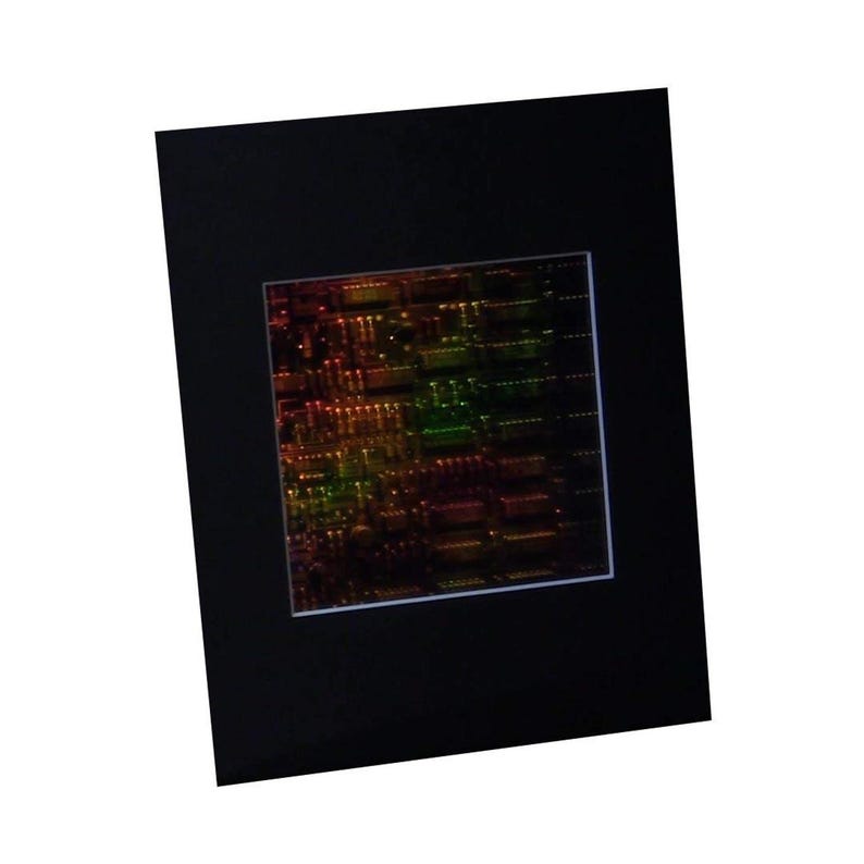 Puede incluir: Una imagen enmarcada de una placa de circuito con un acabado iridiscente de colores. La placa est&aacute; iluminada desde atr&aacute;s, creando un efecto brillante. Los colores son principalmente rojo, verde y amarillo.