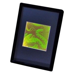 Pu&ograve; includere: Un'opera d'arte incorniciata con un vibrante serpente verde neon. Le squame e la forma del serpente sono dettagliate su uno sfondo blu scuro. L'opera d'arte &egrave; racchiusa in una cornice nera, creando un contrasto sorprendente.