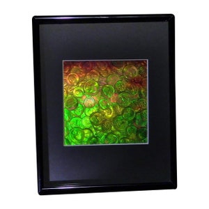 Peut inclure: Une œuvre d'art encadrée représentant un gros plan d'une pile de pièces irisées, avec un dégradé de couleurs allant du vert à l'orange.