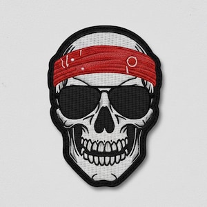 May include: Embroidered patch of a skull wearing sunglasses and a red headband. The skull is white with black outlines and details, including teeth. The patch has a black border and is set against a white background.