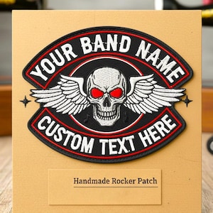 May include: An embroidered patch in black, red, and white, featuring a skull with wings and the text "YOUR BAND NAME" and "CUSTOM TEXT HERE". The patch is displayed on a tan card with "Handmade Rocker Patch" text.